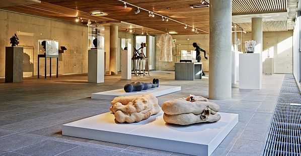 De binnenzaal van Museum Beelden aan Zee met op witte plateaus en sokkels sculpturen en beelden