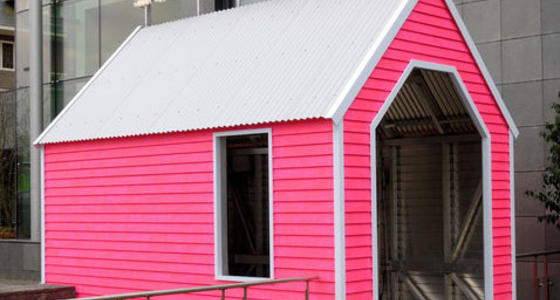Een knal roze houten huisje met wit dak, vormt de entree naar het restaurant