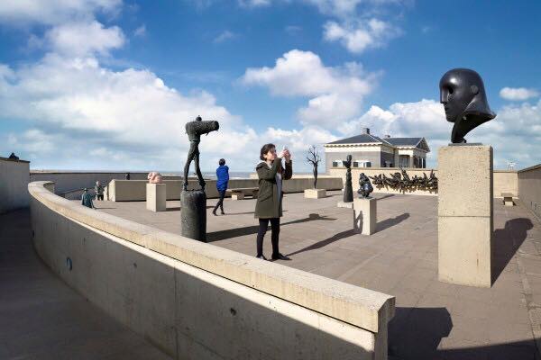 Een vrouw maakt een foto op een van de buiten terrassen van het museum waar verschillende beelden zijn tentoongesteld op sokkels