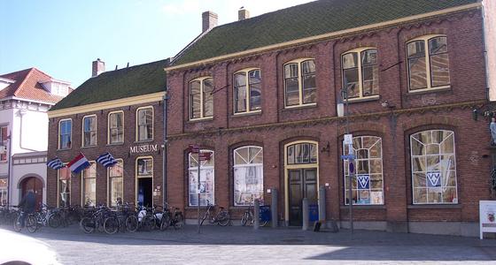 Het donkerrode bakstenen gebouw met grijze dak en cremekleurige vensters en dakgoot is in hetzelfde pand gevestigd als de VVV