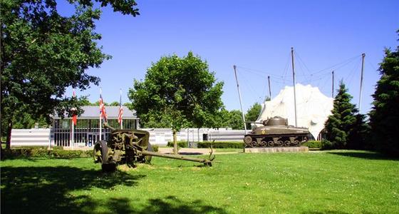 Buiten op het terrein bij het museum staan op het gras twee tankwagens tentoongesteld.