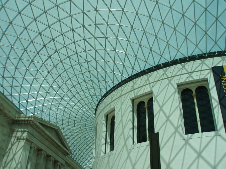 Een foto van het glazen dak van het musuem vanaf de binnenzijde genomen. Rechts een ronde witte zaal