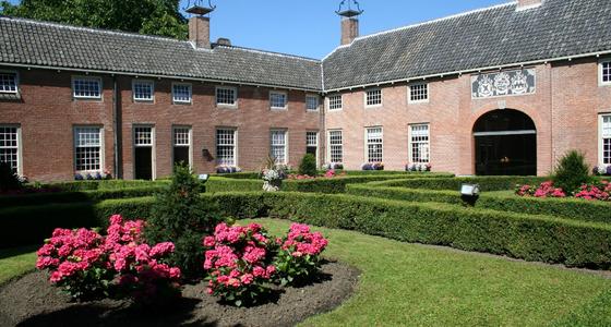 De binnenplaats van het hofje is groen gekleurd door de heggen en grasveldjes met daarin rozenperkjes. Het gebouw is van licht oranje bakstenen met een grijs pannen dak.