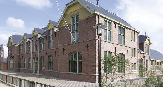 Een rood bakstenen statig gebouw met twee verdiepingen omringd door een heuphoog hek