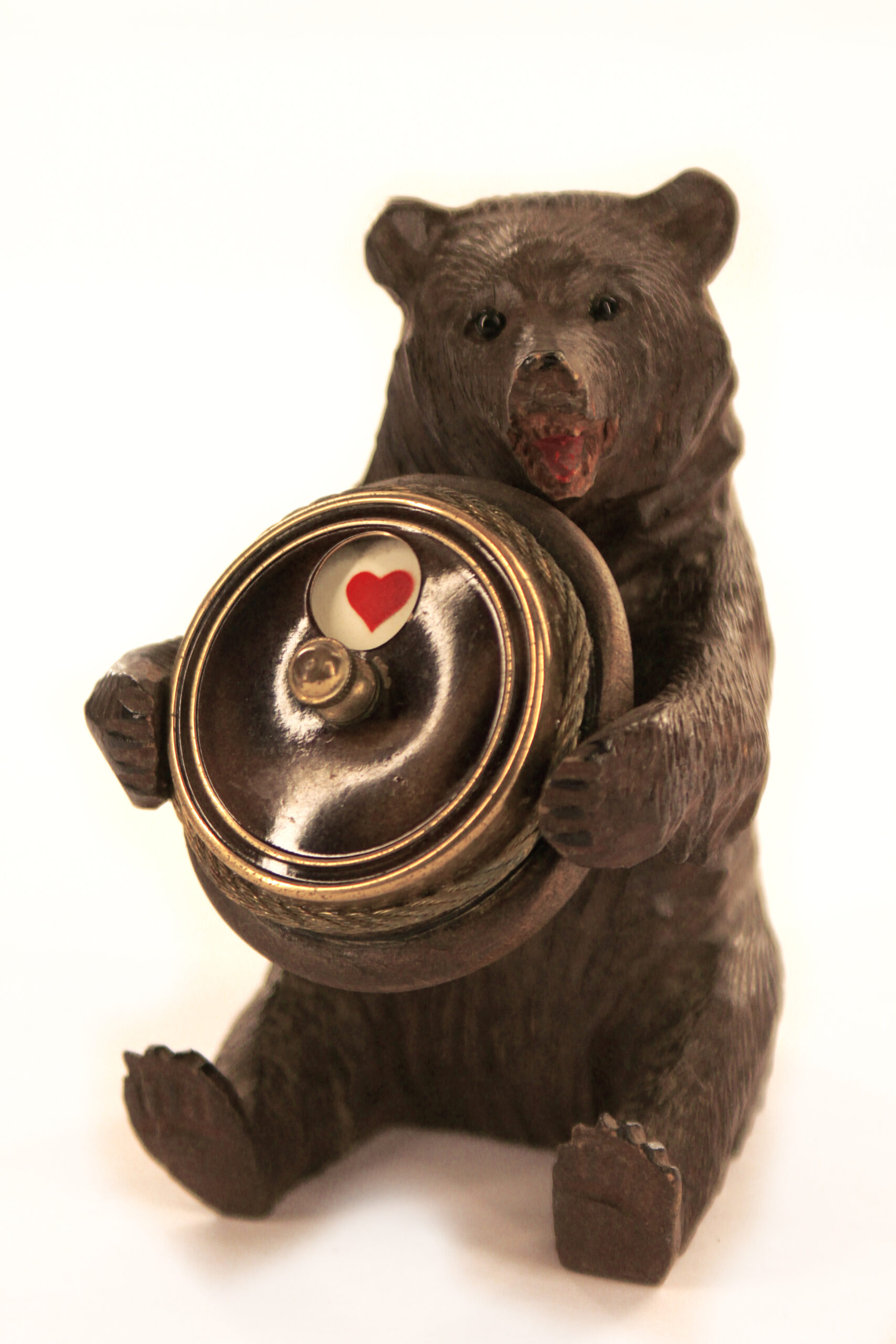 Een foto van een beeldje van een beer, zittend op zijn kont. De Beer heeft een rond voorwerp in zijn poten met daarop een hartje, een van de symbolen van een kaartspel