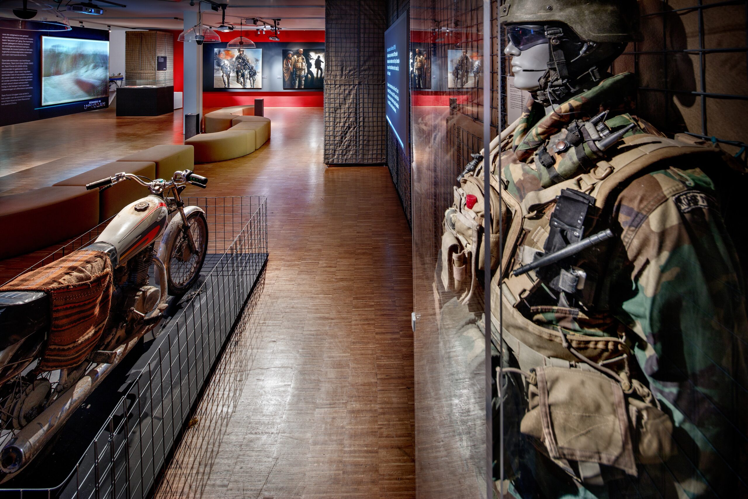 Een museumzaal met vitrines en plateaus met verschillende attributen van de marine. op de voorgrond oa een uniform en legermotor.