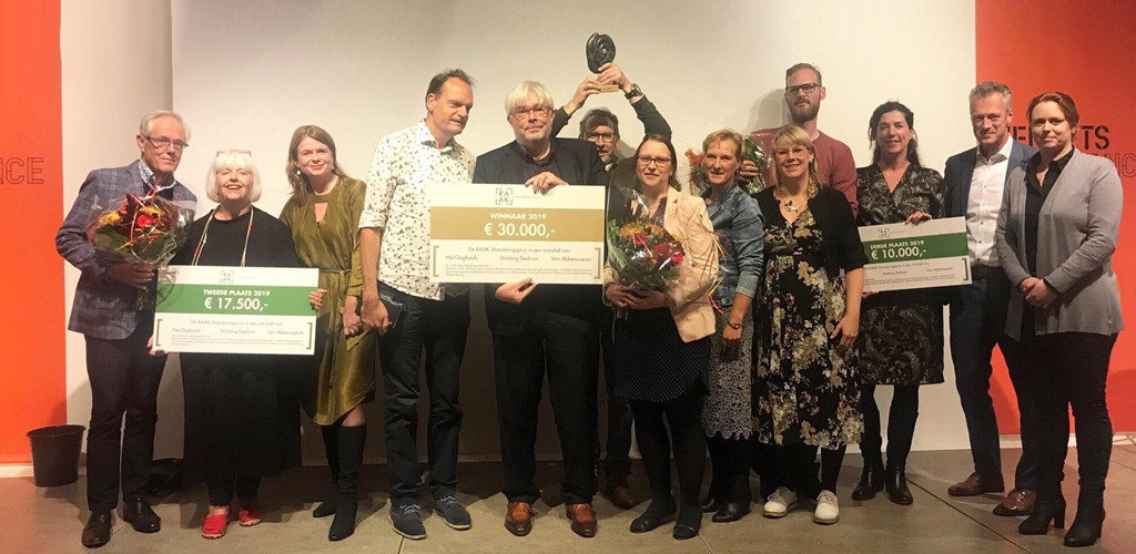 De 3 finalisten met ieder hun gewonnen prijs staan te stralen naast VIncent Bijlo die de prijs uit mocht reiken, en de initiatiefnemers Edith Mulder en Petra van der Wal (Oogfonds), Mariska Sturkenboom (Dedicon) en Marleen Hartjes (van Abbe museum)