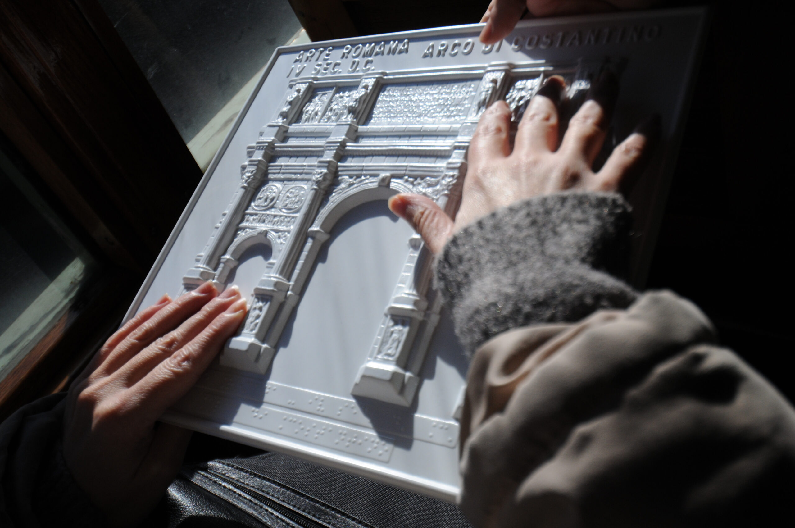 twee handen voelen aan een driedimensionale weergave van een architectonisch gebouw. Een Arque the triomphe boog