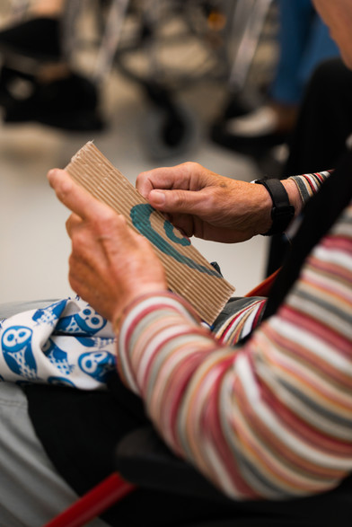 Iemand voelt met twee handen aan een voorwerp uit de collectie dat zij op aar schoot vast houdt