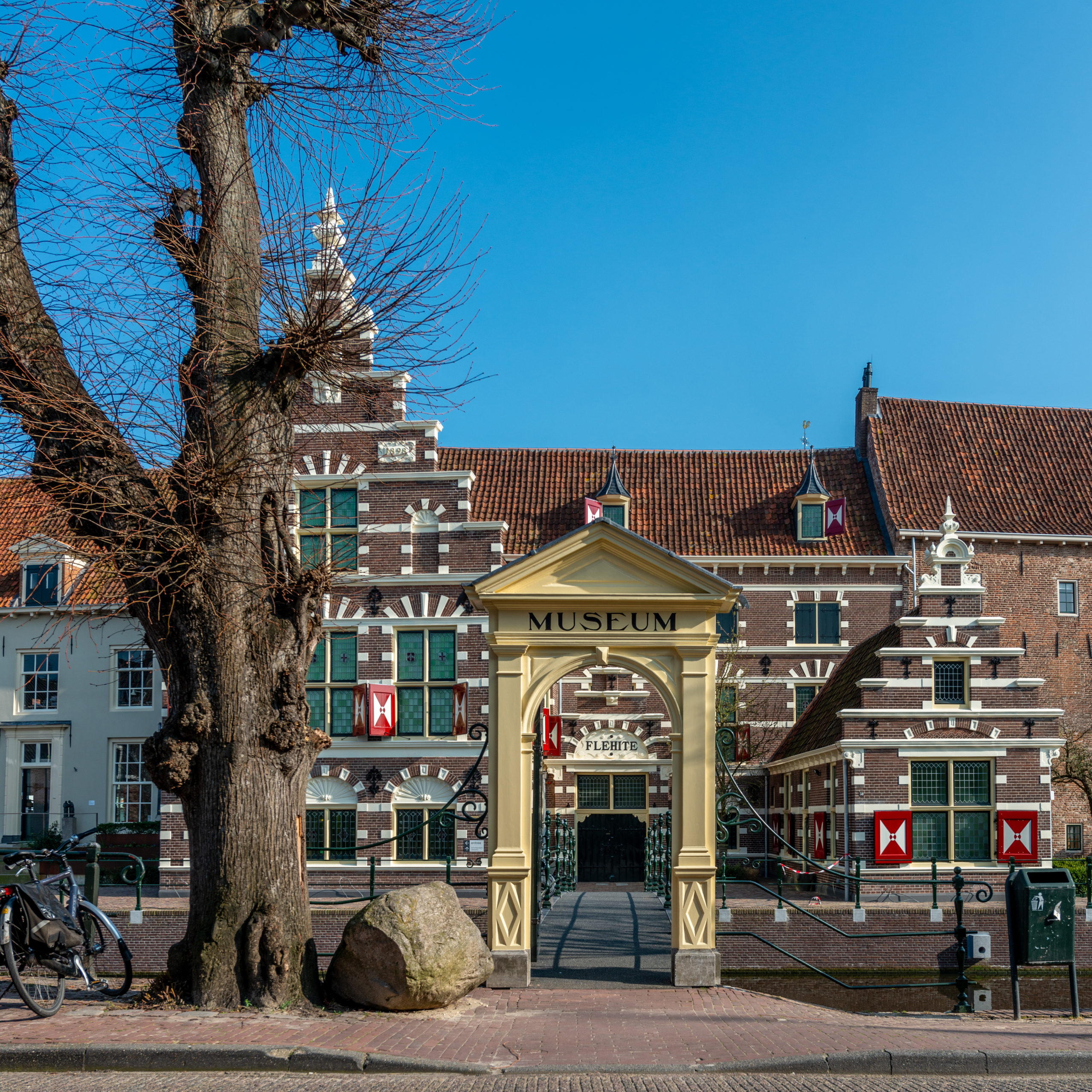 Het rood bakstenen gebouw ziet er vrolijk uit door de rode luiken en witte ingemetselde strepen en bogen boven de ramen