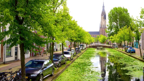 een foto van een van de grachten van Delft met op de achtergrond een kerktoren.