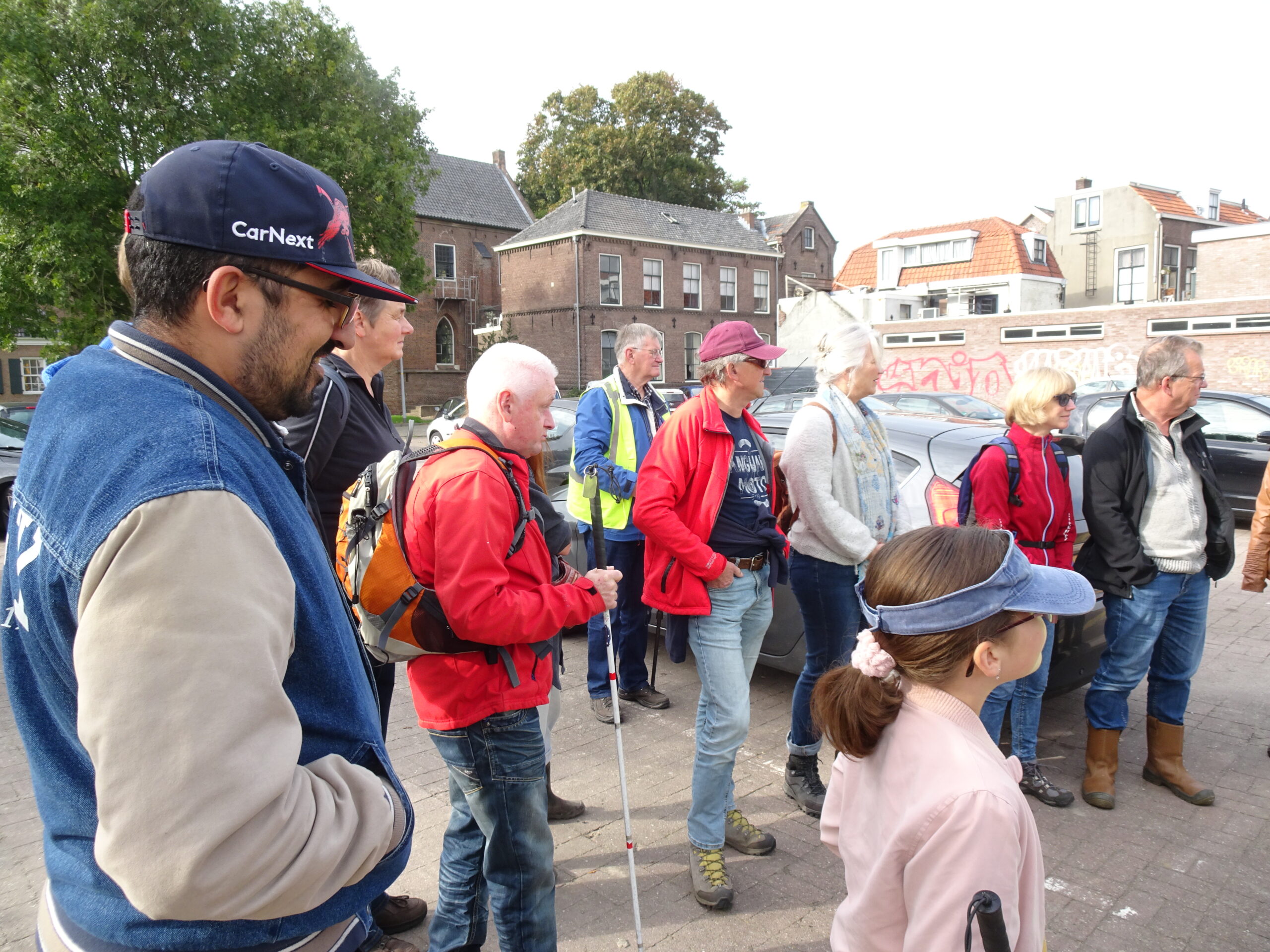 Op het nabij gelegen parkeerterrein verzamelen de deelnemers zich voor we de opgraving gaan bezoeken