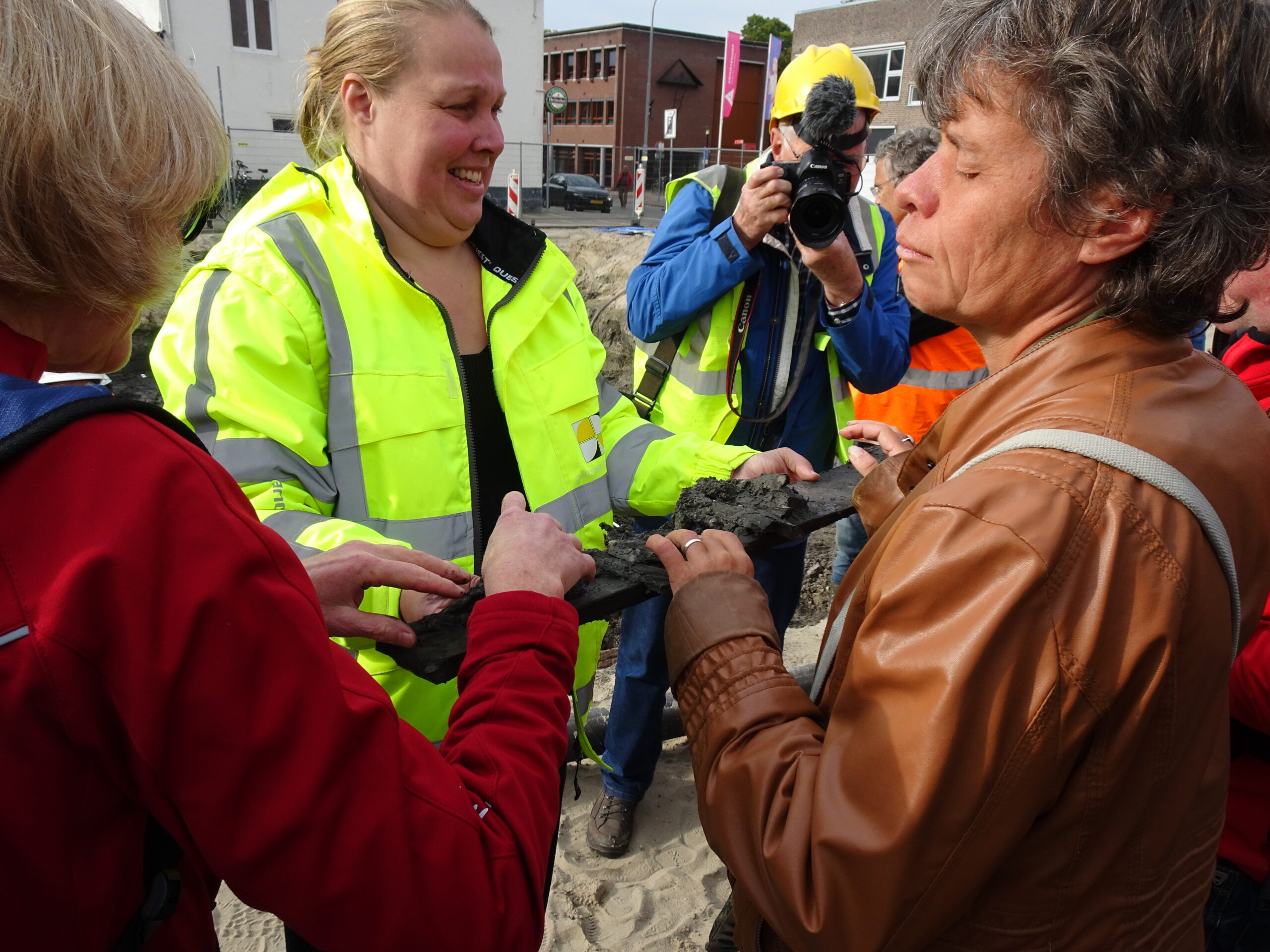 voorzichtig voelen de deelnemers aan de net opgegraven planken van een wijnvat