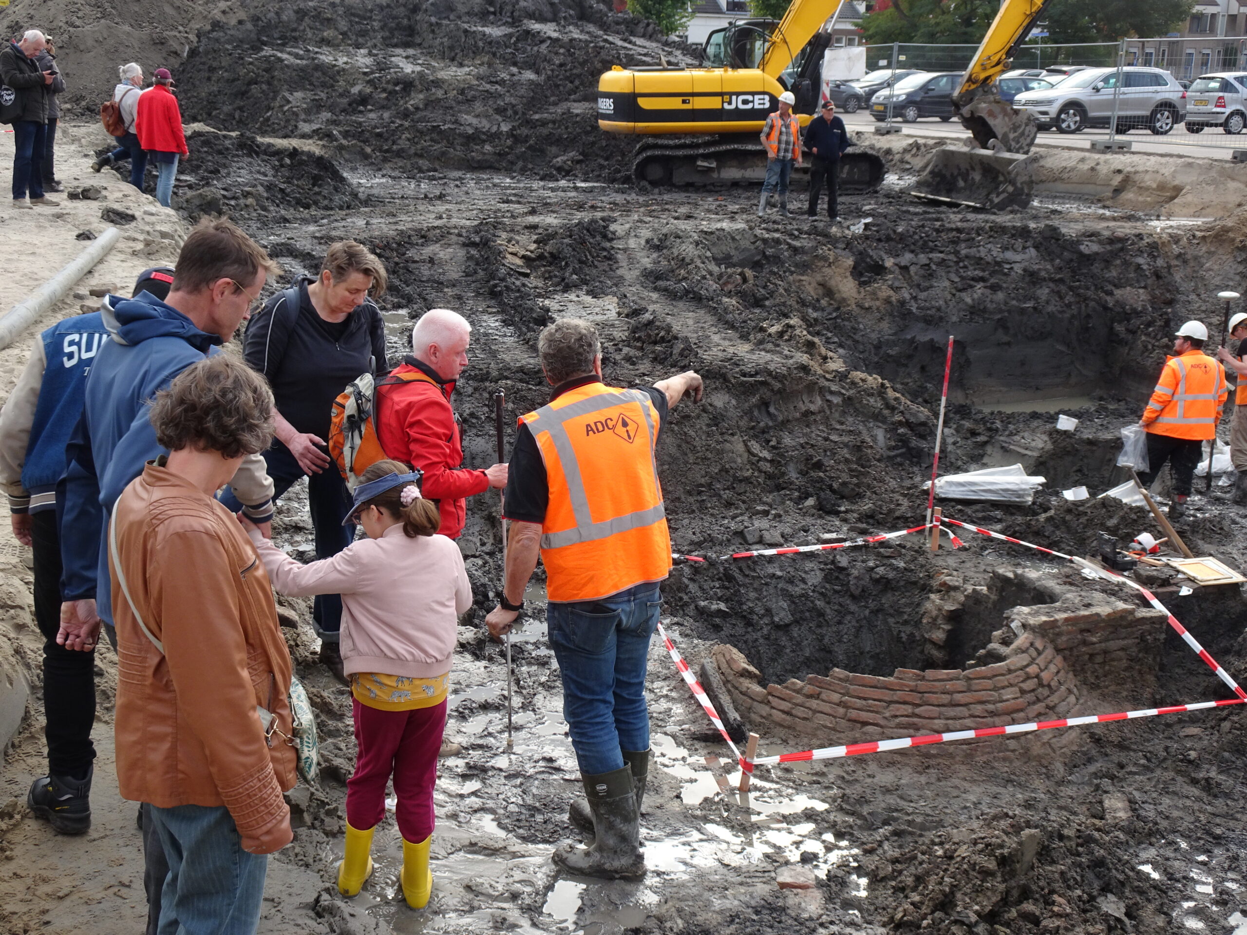 een groep deelnemers aan de rand van de put met de opgegrave beerput voor hen