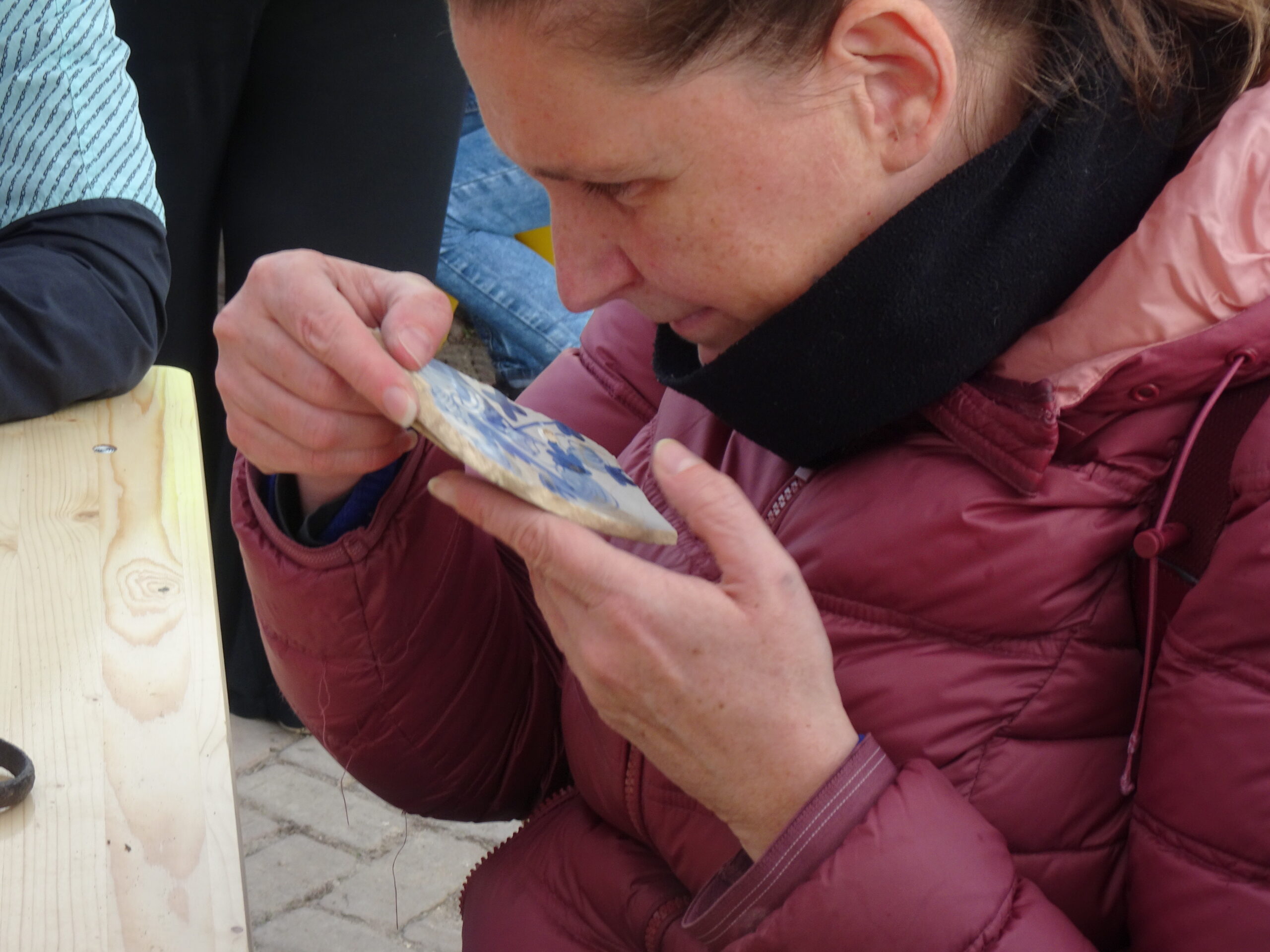 Een vrouw bekijkt een blauw beschilderde scherf van heel dichtbij