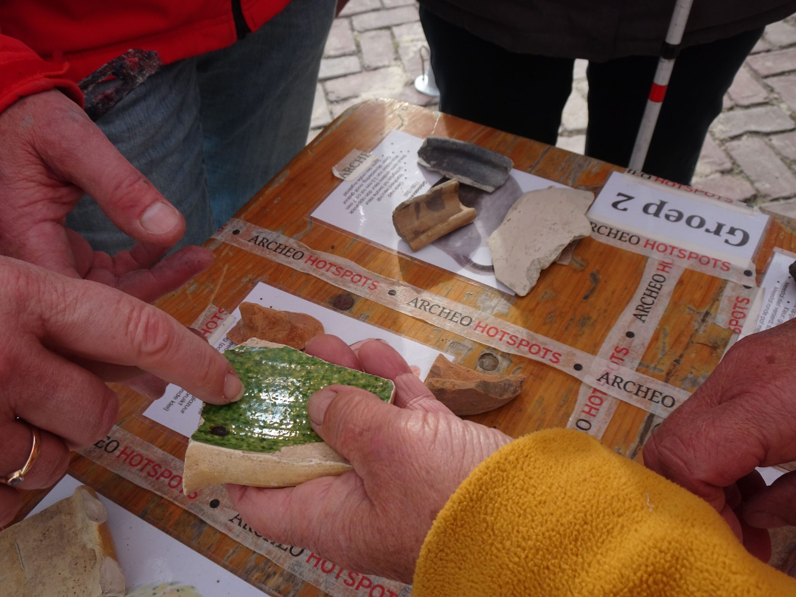 de hand van een deelnemer met een groene scherf van een pot