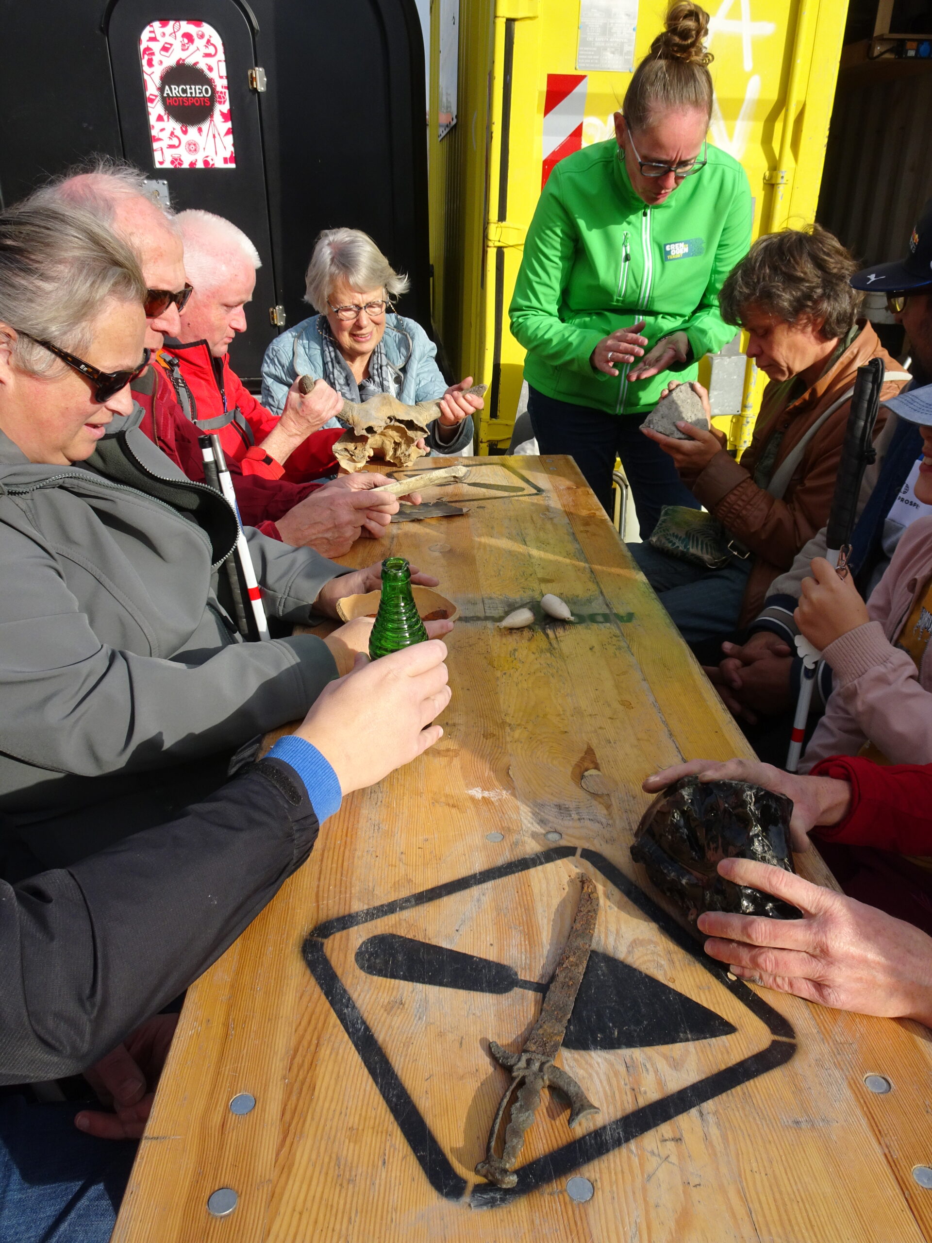 aan tafel een grote groep deelnemers die allemaal een andere vondst ontdekken met hun handen