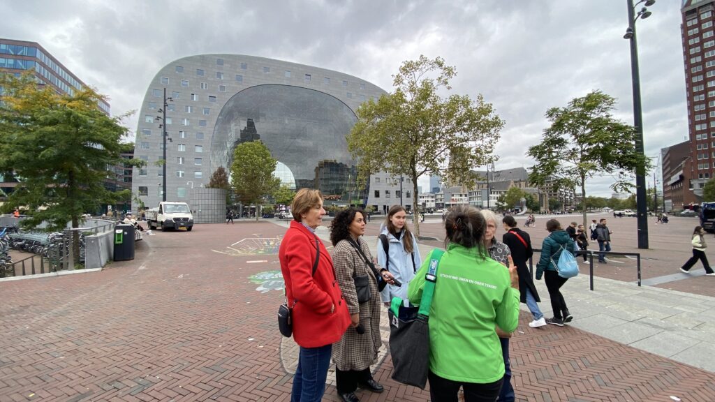 Joan tijdens een rondleiding met op de achtergrond de Markthal